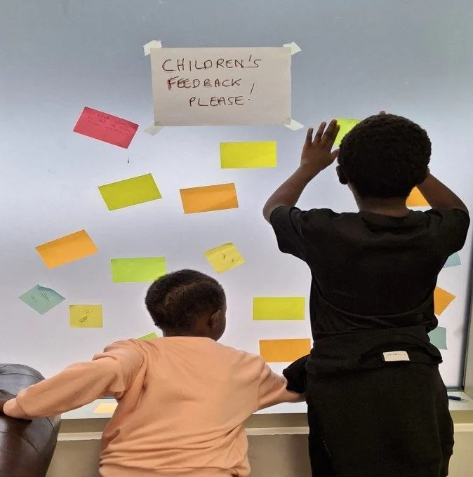 Children adding post-it note feedback on the Summer Programme